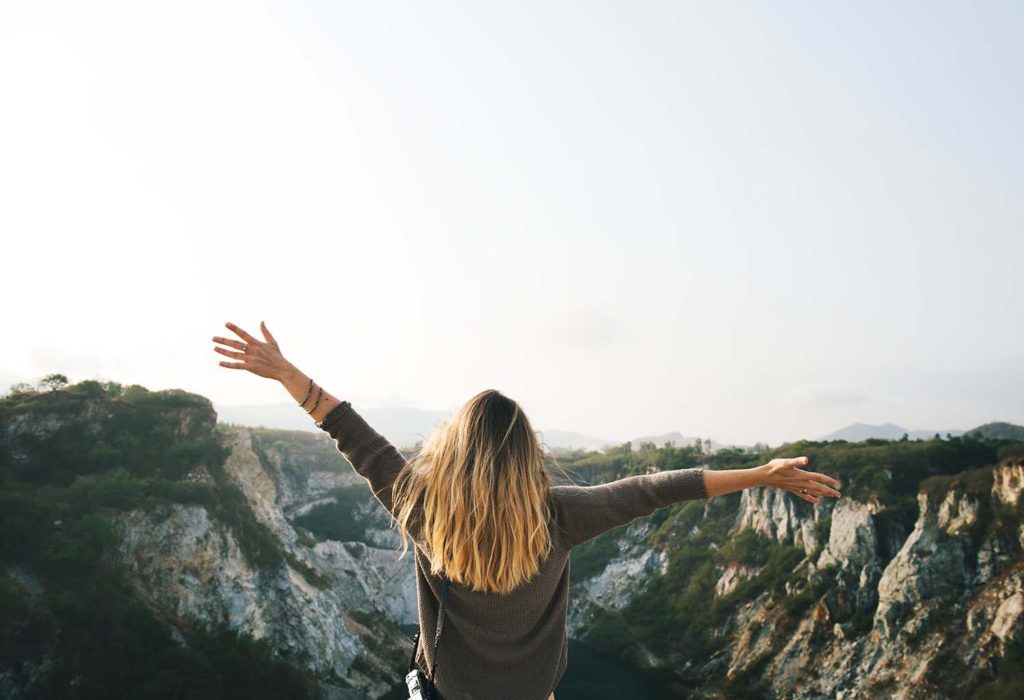 viajera levantando los brazos de felicidad en un paisaje